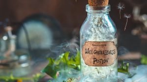 Glass potion bottle with dandelion seeds and handcrafted label in a magical still life with smoke