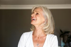 laughing older woman standing inside home